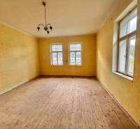 A room in a family house with a wooden floor, yellow walls, and a pendant light.