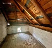 Attic space in a family house with a wooden beam ceiling and a small window.