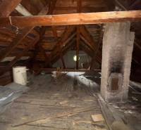 The attic of a family house with a wooden structure and a brick chimney.