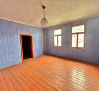 A room in a family house with a wooden floor and blue wallpaper.