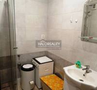 Bathroom with a sink, shower, and washing machine in a 2-room apartment.