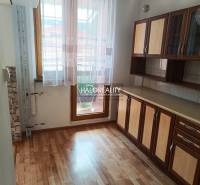 A kitchen in a 3-room apartment with a wooden floor and a kitchen unit.
