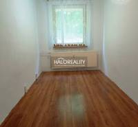 A narrow room with a wooden floor, a window, and a radiator in a 3-room apartment.