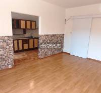 Living room in a three-room apartment with wooden flooring and a kitchenette.