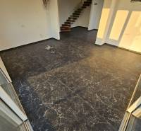 Recreational apartment with dark flooring, white walls, and a staircase.