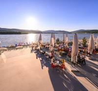 Summer terrace by the water in Ružiná, with a view of the lake and mountains.