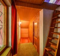 Interior of a cabin with stairs, wooden paneling, and a view through the window.