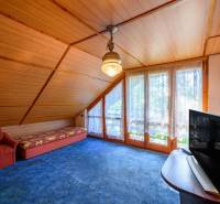 Cozy space in a cabin with an armchair, sofa, TV, and large windows with a view.