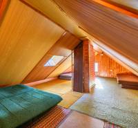 Attic in a cabin with wooden walls and sofa beds.