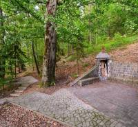 The cottage by the lake in Ružiná with a stone bench and a wooden shelter for wood.