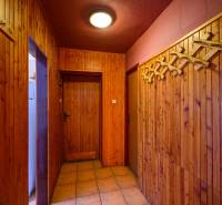 A wooden interior of a cabin with a coat rack and lighting offers a cozy atmosphere.