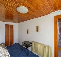 Wooden ceiling, bed, table, blue carpet, lamp on the wall in the cabin.