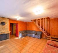 Interior of a cabin with a brick fireplace, wooden paneling, and a staircase.