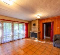 The interior core of the cottage with a fireplace, large windows, and red curtains.