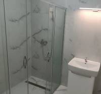 Bathroom with a glass shower enclosure in a 2-room apartment.