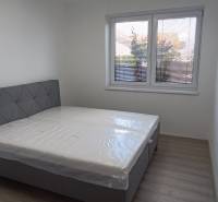 A bedroom with a bed and a window in a 2-room apartment, light walls and floor.