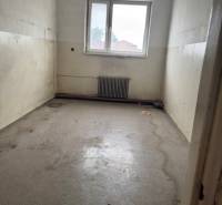 Empty commercial spaces with a window and gray floor.