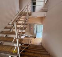 A staircase in a building with a wooden floor and metal railing.