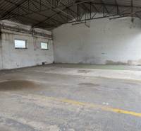An empty interior of a hall in a building, available space with a concrete floor and skylights.