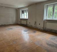 An abandoned room in a building with a wooden floor and large windows.