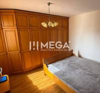 Bedroom in a 3-room apartment with a wooden wardrobe, bed, and window with blinds.