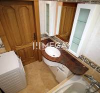 Bathroom with wooden door, washing machine, sink, and tiles in a 3-room apartment.