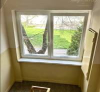 A corridor with a staircase and a window in a building, greenery outside. Offers a 2-room apartment.