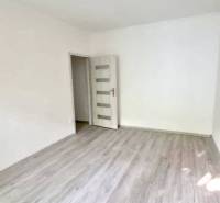 Empty room with laminate flooring in a 2-room apartment, neutral walls, and a ceiling light.