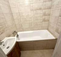 Bathroom in a 2-room apartment with a bathtub and a sink, tiles in beige shades.