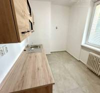 A kitchen with a wooden cabinet in a 2-room apartment, also showing a radiator and a window.