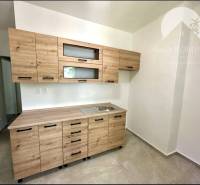 Kitchen in a 2-room apartment with a wooden cabinet and ceramic floor.