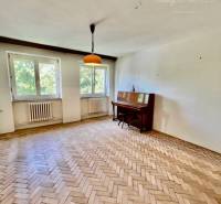 A bright living room in a two-room apartment with a parquet floor and a large window.