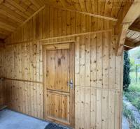 A wooden structure with a sloped roof and entrance door, view from the outside.