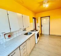 A kitchen in a 2-room apartment with a yellow ceiling, white cabinets, and flooring.