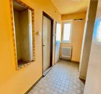 A hallway in a 2-room apartment with a tiled floor and a mirror on the wall.