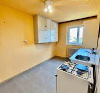A kitchen in a 2-room apartment with a gas stove, a cupboard, and a window.