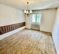 A room in a 2-room apartment with a wooden floor and a chandelier, simple interior.