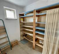 Storage space in a 2-room apartment with shelves and a window, suitable for storage.
