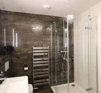 Bathroom with a glass shower enclosure, sink, and chrome ladder in a 3-room apartment.