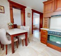 A kitchen with a dining table, chairs, and a wooden kitchen unit in a family house.