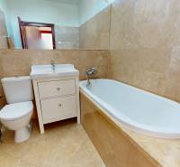 A bathroom in a family house with a bathtub, sink, and toilet, surrounded by ceramic tiles.