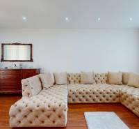 Living room in a family house with a light-colored sofa and a wooden sideboard.