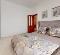 A bedroom in a family house with a bed and a lamp, a wardrobe opposite the head of the bed.