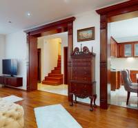 Living room in a family house with dark furniture and a staircase in the background.