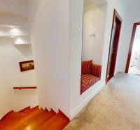 A hallway with a staircase, a seating alcove, and elegant wooden door frames in a family house.