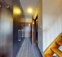 Hallway of a 2-room apartment with built-in wardrobes and a wooden staircase.