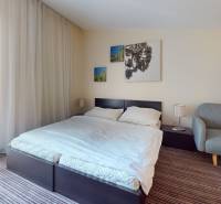Bright bedroom in a 2-room apartment with a bed, sofa, and balcony.