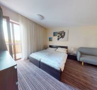 A bedroom in a 2-room apartment with a bed, a couch, and a balcony.