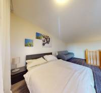 A bedroom in a two-room apartment with a comfortable bed and a railing by the staircase.
