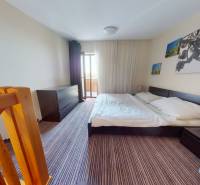 Bedroom in a 2-room apartment with a staircase, a large bed, and photographs on the wall.